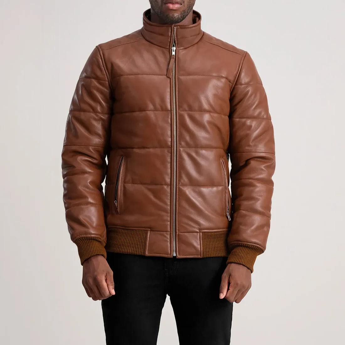 Brown leather jacket worn by a person on a plain background