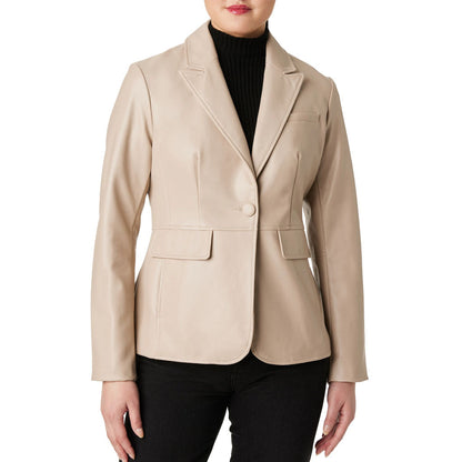 A woman wearing a structured beige faux-leather blazer over a black ribbed turtleneck and black pants, shown from the lips down against a plain white background.