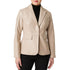 A woman wearing a structured beige faux-leather blazer over a black ribbed turtleneck and black pants, shown from the lips down against a plain white background.